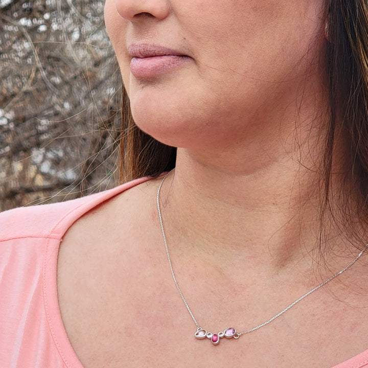 5 stone cluster necklace on model in front of wooded background