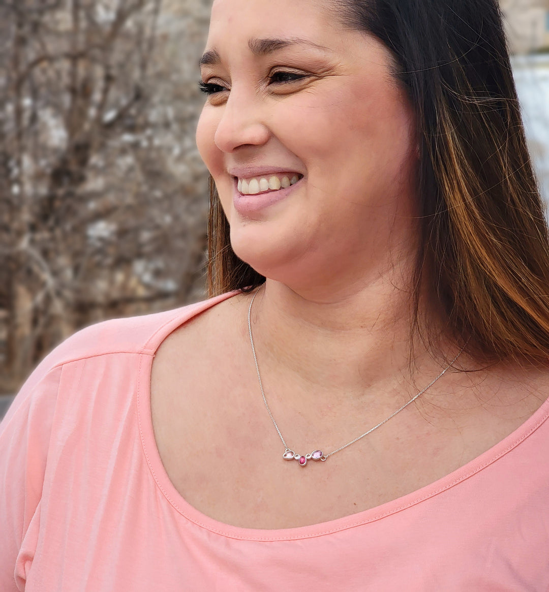 5 stone pink cluster neckalace on smiling model in front of wooded area