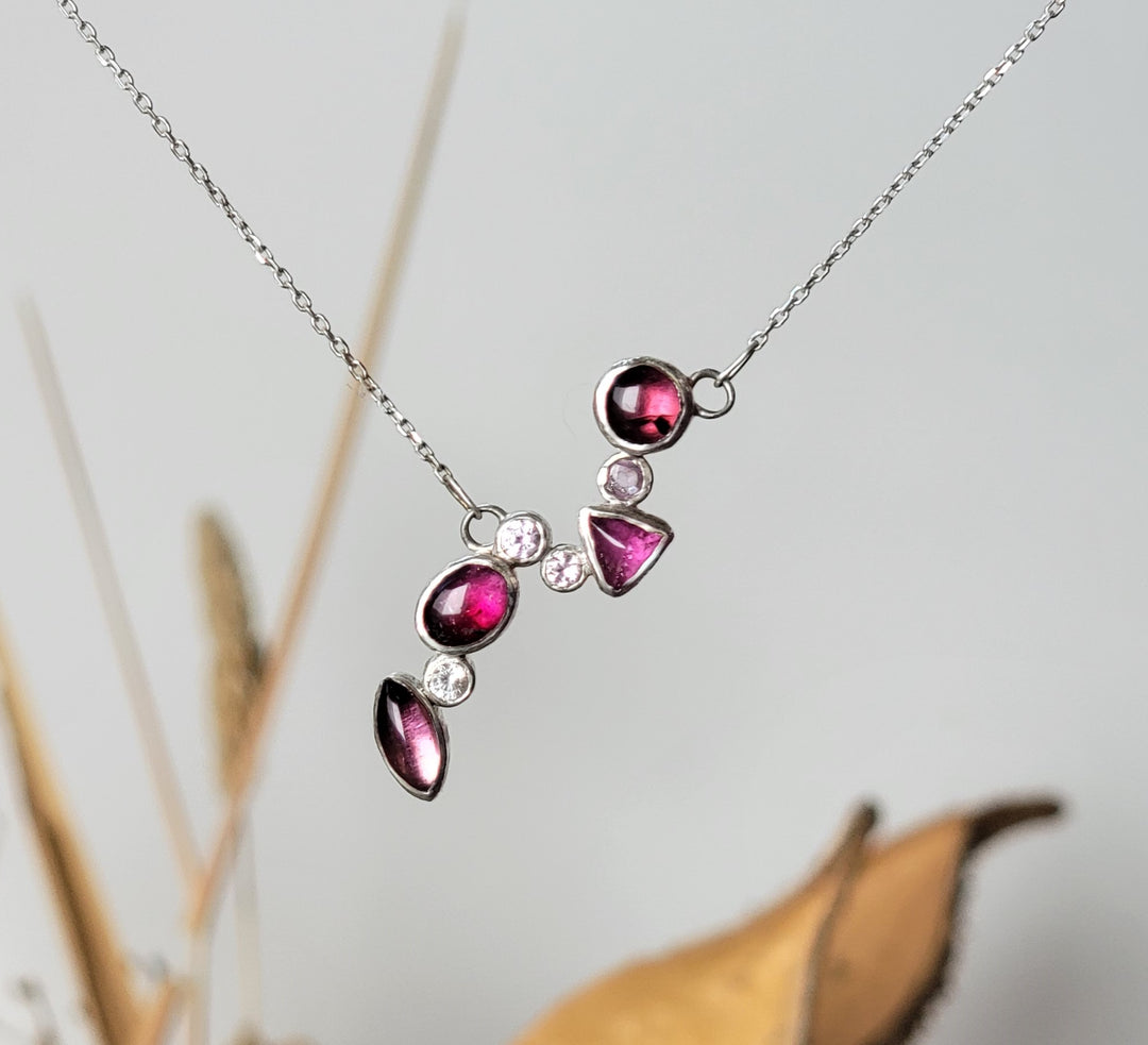 one of a kind cluster necklace design that cascades in a diagonal down the frame. Roung pink tourmaline, 3mm pink sapphire, trillion pink tourmaline, two 3mm pink sapphires, oval pink tourmaline, 3mm white sapphire, trillion pink tourmaline
