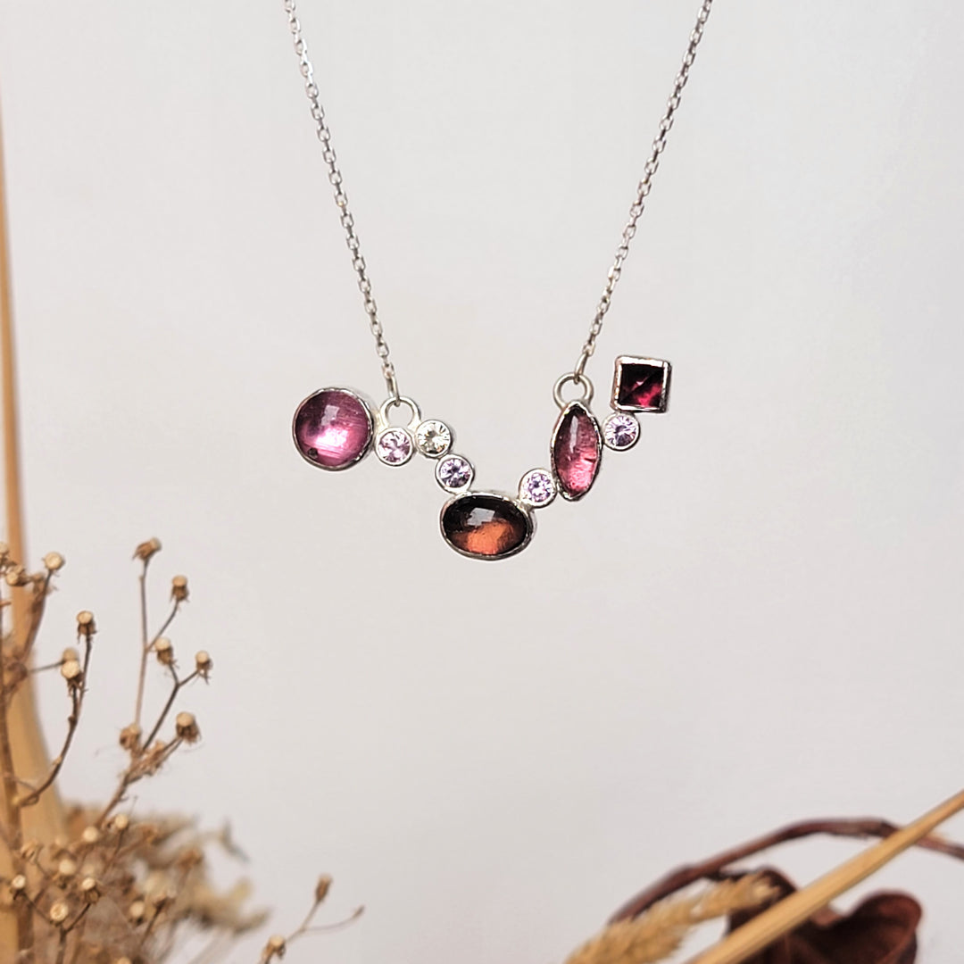 Magenta and deep baby pink tourmaline cluster necklace with light baby pink sapphires on white background.