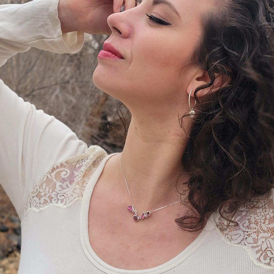 Model posing in front of wooded area. She is wearing the Starry Night Hues of Pink necklace and Wolf Moon Earrings.
