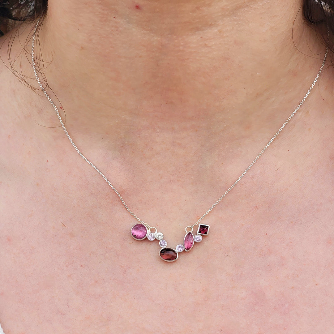 close up of magenta and baby pink tourmaline cluster necklace on model. 